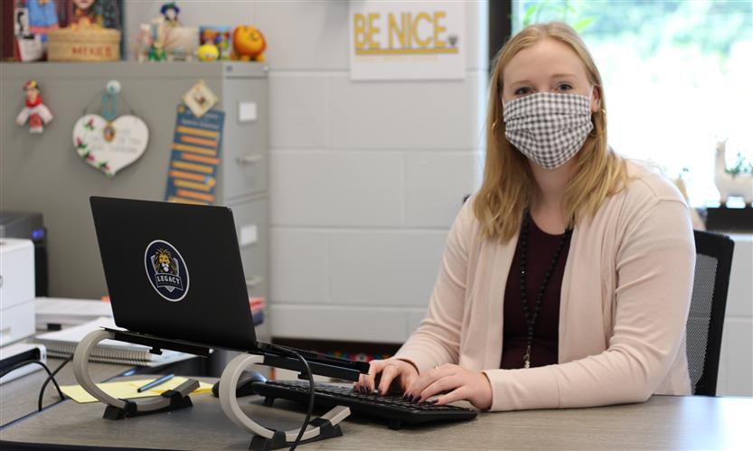 Teacher smiles while sitting at desk